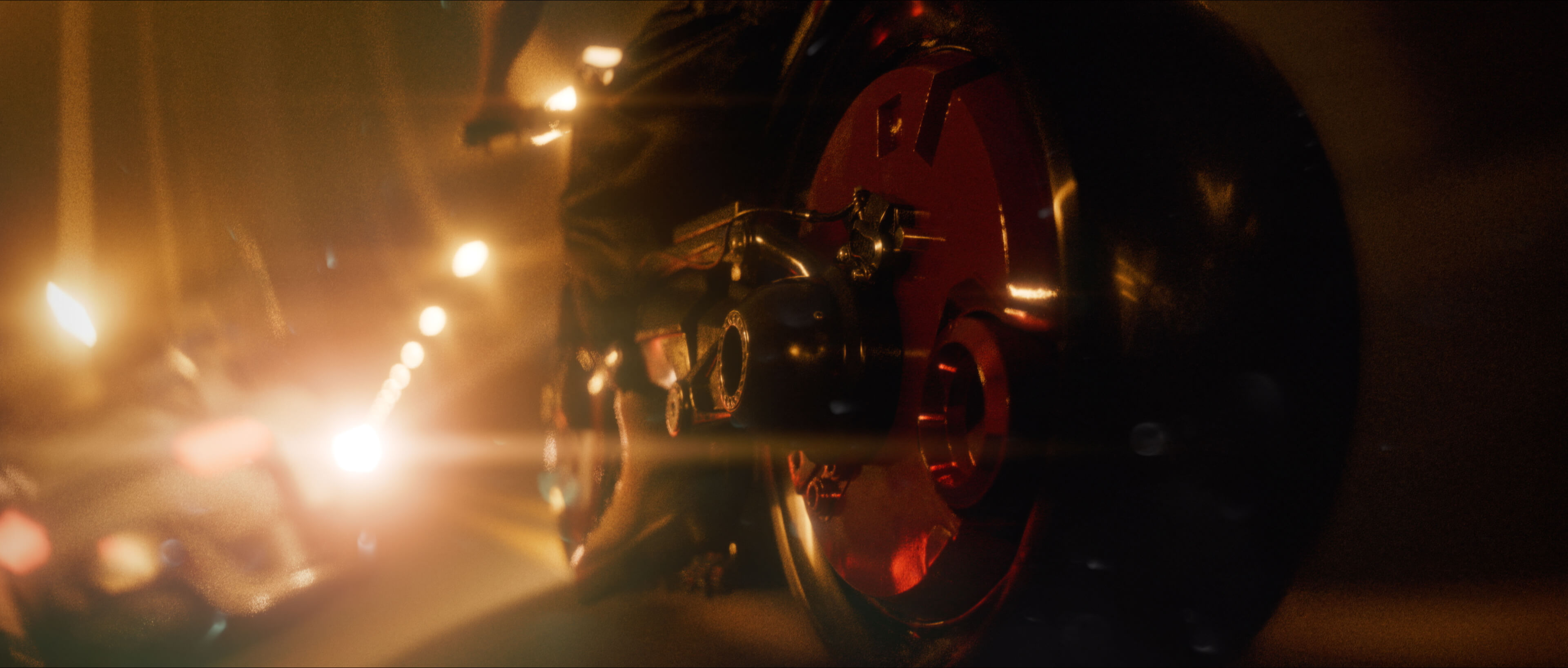 Red motorcycle wheel caught in warm lens flares